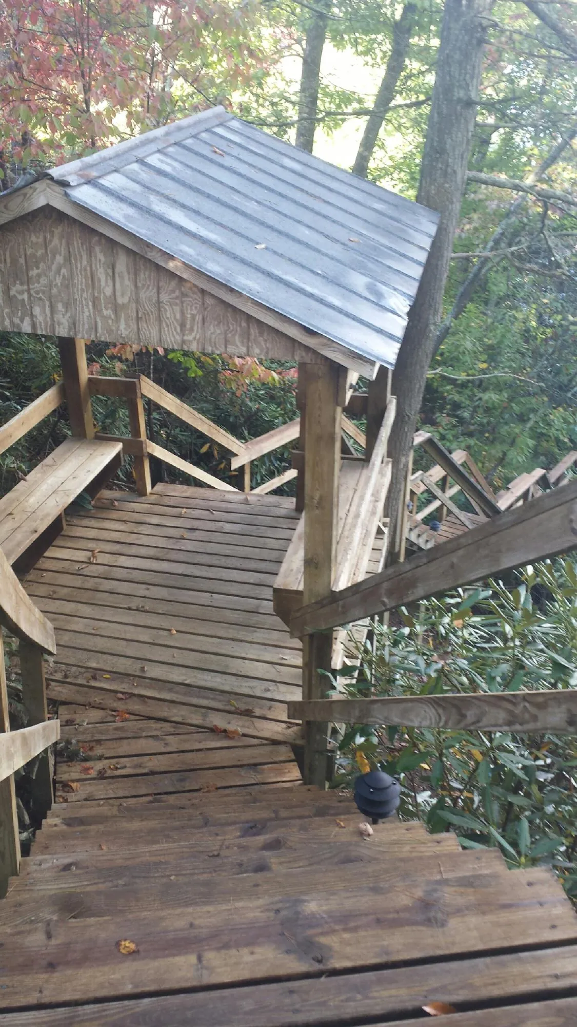 Metal roofed shelter over wooden steps on a wooded walkway — Skylight Repair & Installation work by our crew in Granby