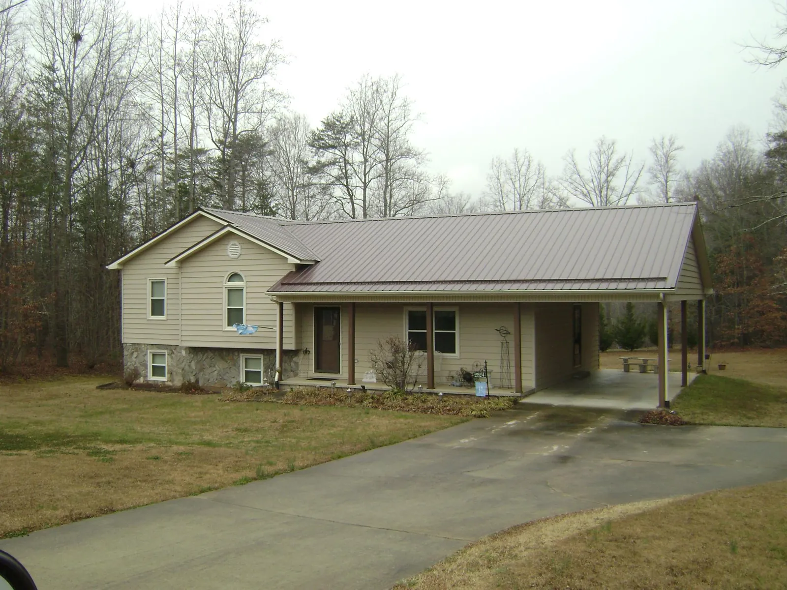 Brown metal roof on a tan split level home with an attached carport in Granby
